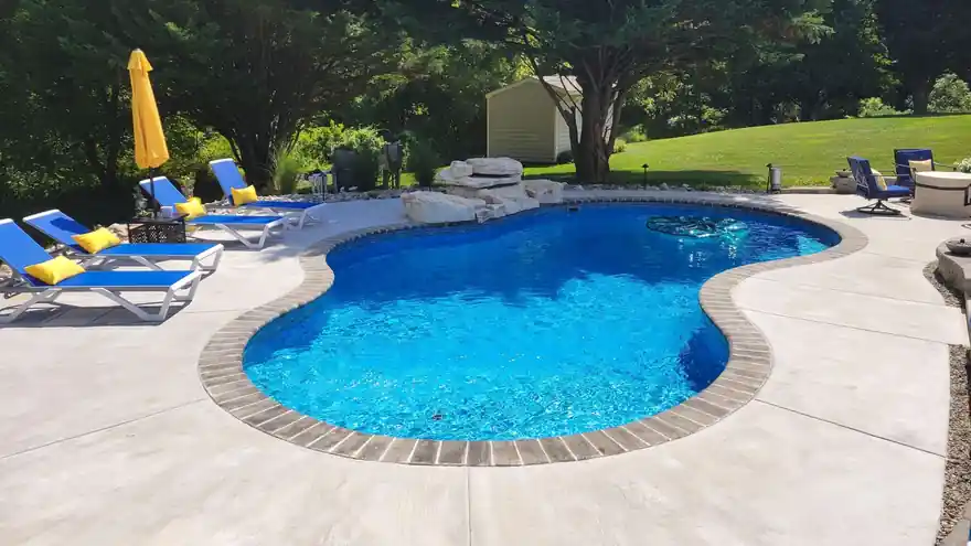 Patterned blue vinyl liner seen through clear water, concrete deck and umbrellas